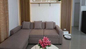 A modern living room with a sectional sofa, a round coffee table with a vase of flowers, and a wall-mounted sign that reads "Casa de Amor". - Newly Furnished, Modern 3-bedroom house with AC in lovely Dauis  beach. (Dauis)