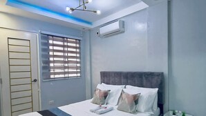 Ein modernes Schlafzimmer mit Bett, Nachttischen, einer Klimaanlage und einem Fenster mit Jalousien.