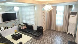 Ein modernes Wohnzimmer mit einer Couch, einem Couchtisch und einem an der Wand montierten Fernseher.