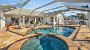 A pool area with a glass ceiling, lounge chairs, and a hot tub.