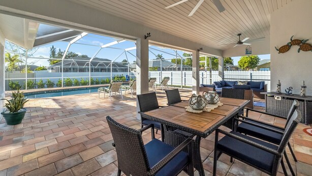 A covered patio area with a pool, outdoor furniture, and ceiling fans.