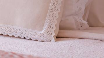 A bed with a white pillow and a white pillowcase with lace trim.