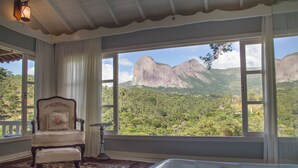 A room with a large window, a chair, a rug, and a bathtub.