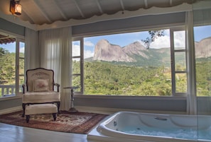Una habitación con un ventanal grande, una silla, una alfombra y una bañera.