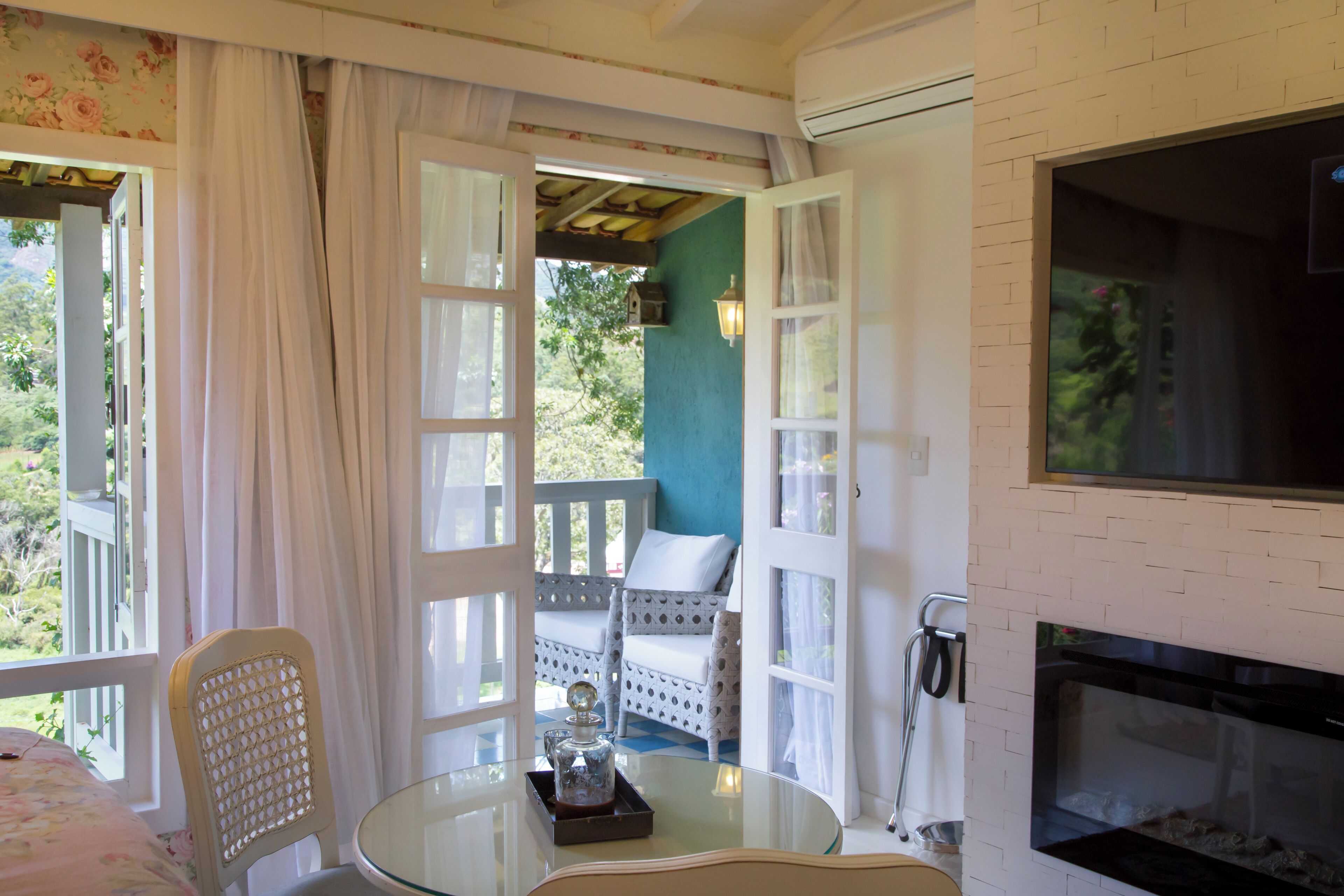 Um quarto com mesa de vidro, uma cadeira, um sofá, lareira e vista para o exterior.