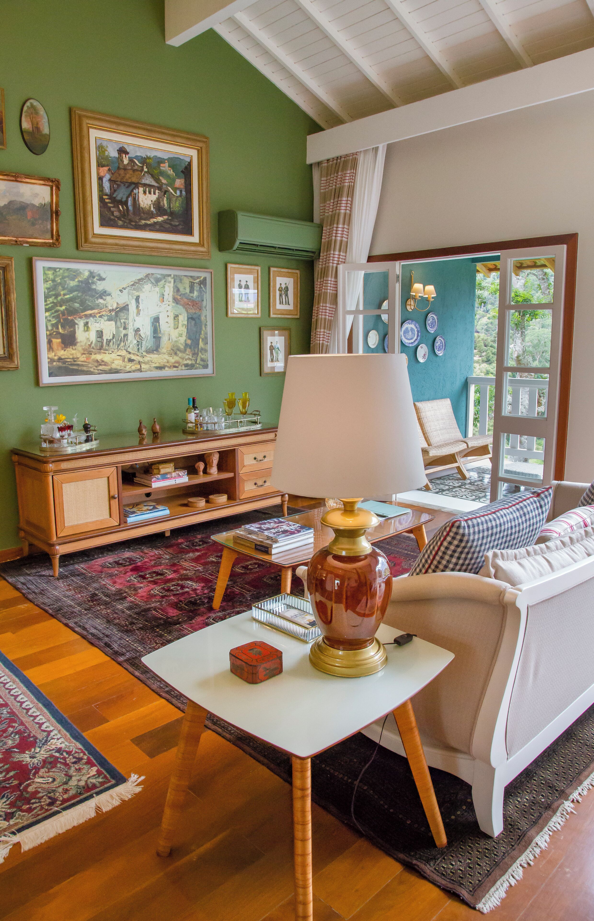 Quarto com um armário de madeira, uma mesa branca com abajur, sofá e uma janela grande.