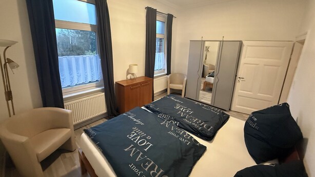 Une chambre à coucher avec un lit, une chaise, une armoire et une fenêtre.