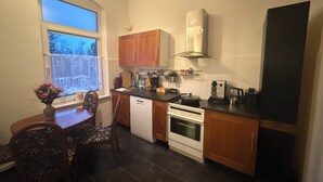 Une cuisine compacte dotée de meubles en bois, d’un lave-vaisselle, d’une cuisinière et d’une machine à café.
