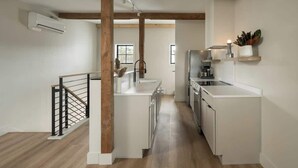 Una cucina moderna con mobili bianchi, travi in legno al soffitto e ringhiera nera.