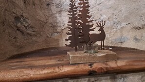 En rustik trähylla med en utskuren relief av en hjort och ett träd, en glasbehållare och en vägg med en strukturerad stenbeklädnad.