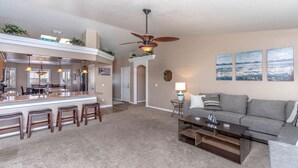 A modern living room with a gray sofa, a coffee table, and a bar area with stools. - Havasu Tropics - Pool, Spa, Game Room, Sleeps14 (Lake Havasu City)