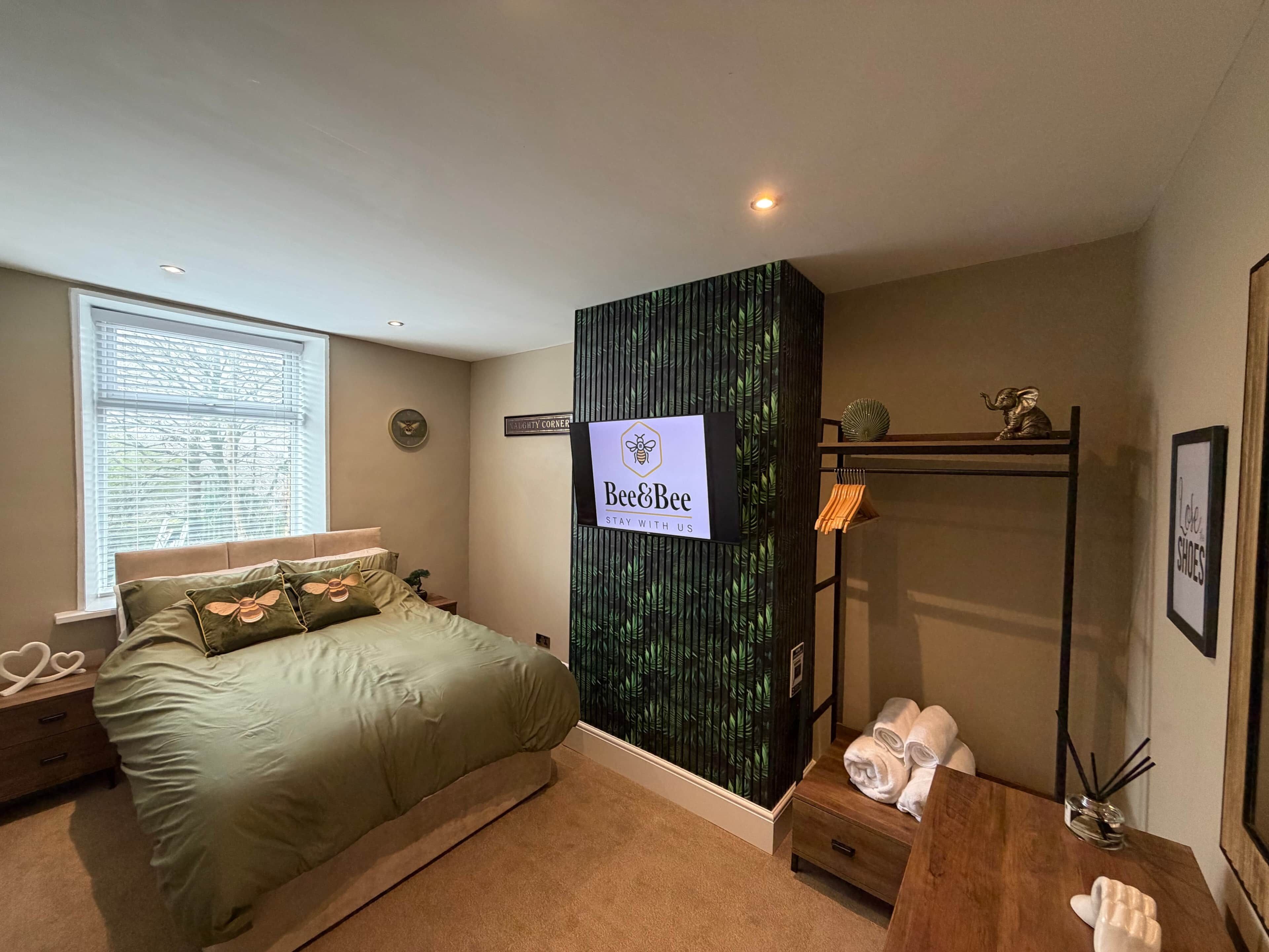 Ein Schlafzimmer mit Bett, Nachttisch, Kommode, Schminktisch und einem Fenster mit Jalousien.