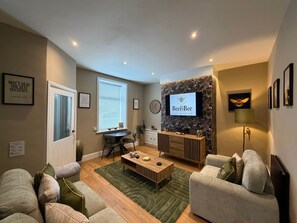 Una sala de estar moderna con un sofá, una mesa de centro y un televisor montado en una pared con diseño.