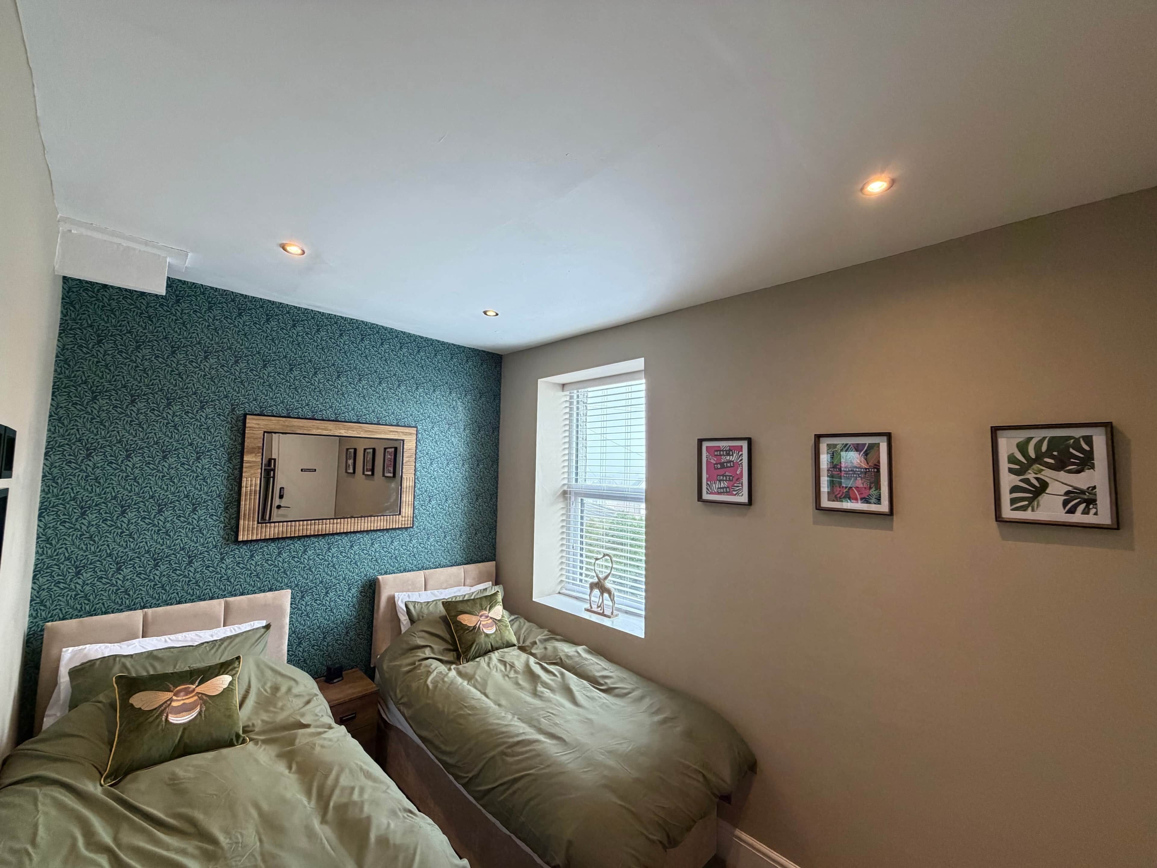 Une chambre avec deux lits, un miroir et trois tableaux encadrés accrochés au mur.