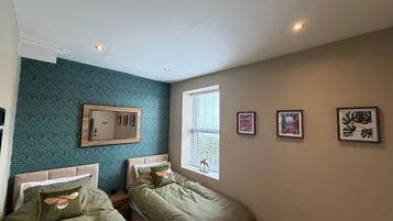 Une chambre avec deux lits, un miroir et trois tableaux encadrés accrochés au mur.