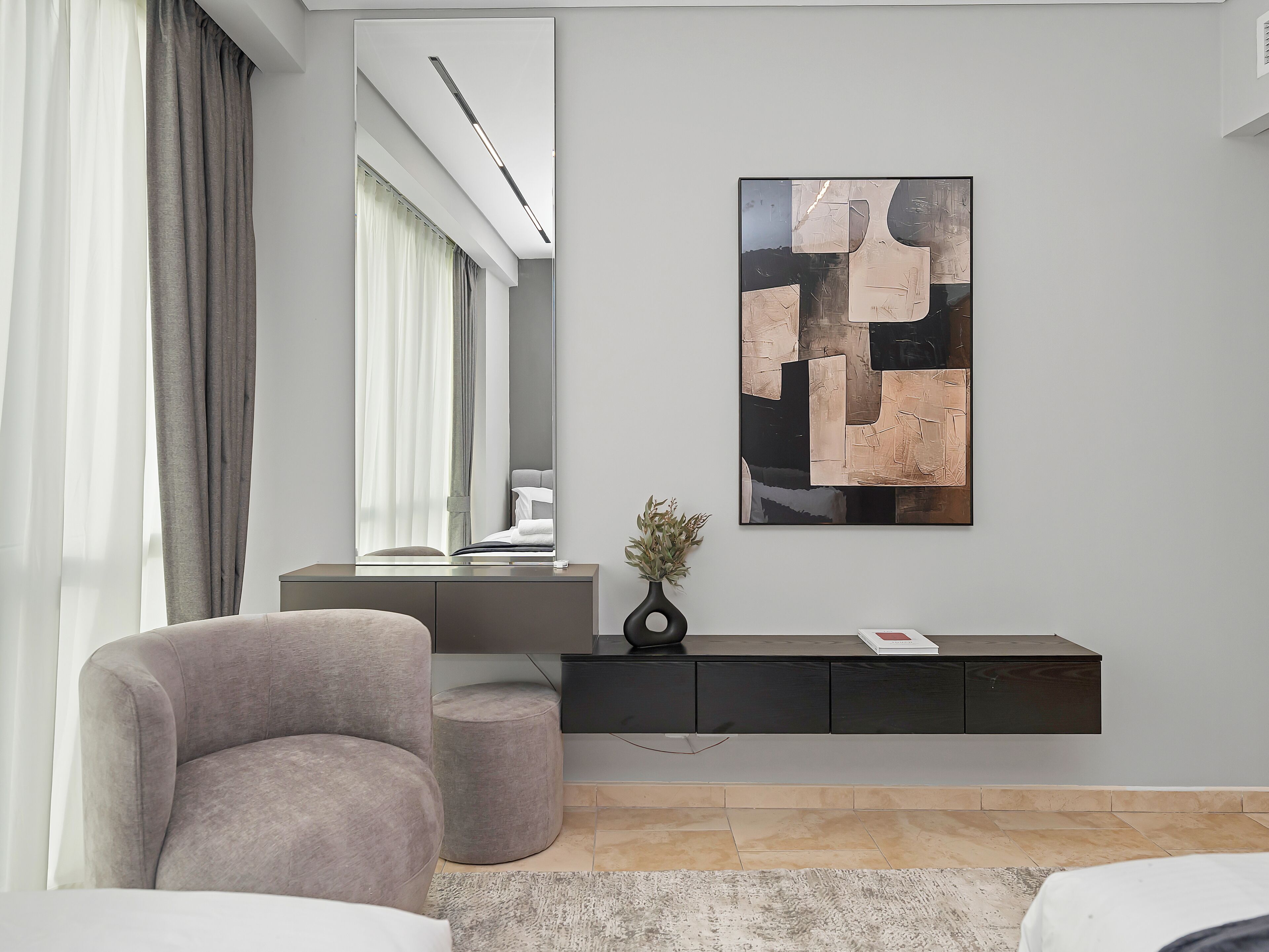 A modern living room with a grey sofa, a black console table, a large abstract painting, and a potted plant.