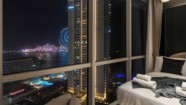 A hotel room with a large window overlooking a cityscape, including a Ferris wheel and high-rise buildings. - Grand JBR PentHouse Style (Dubai)