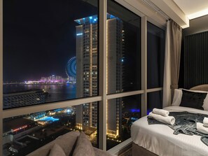 Ein Hotelzimmer mit großem Fenster und Blick auf eine Stadtlandschaft, einschließlich eines Riesenrads und Wolkenkratzern.