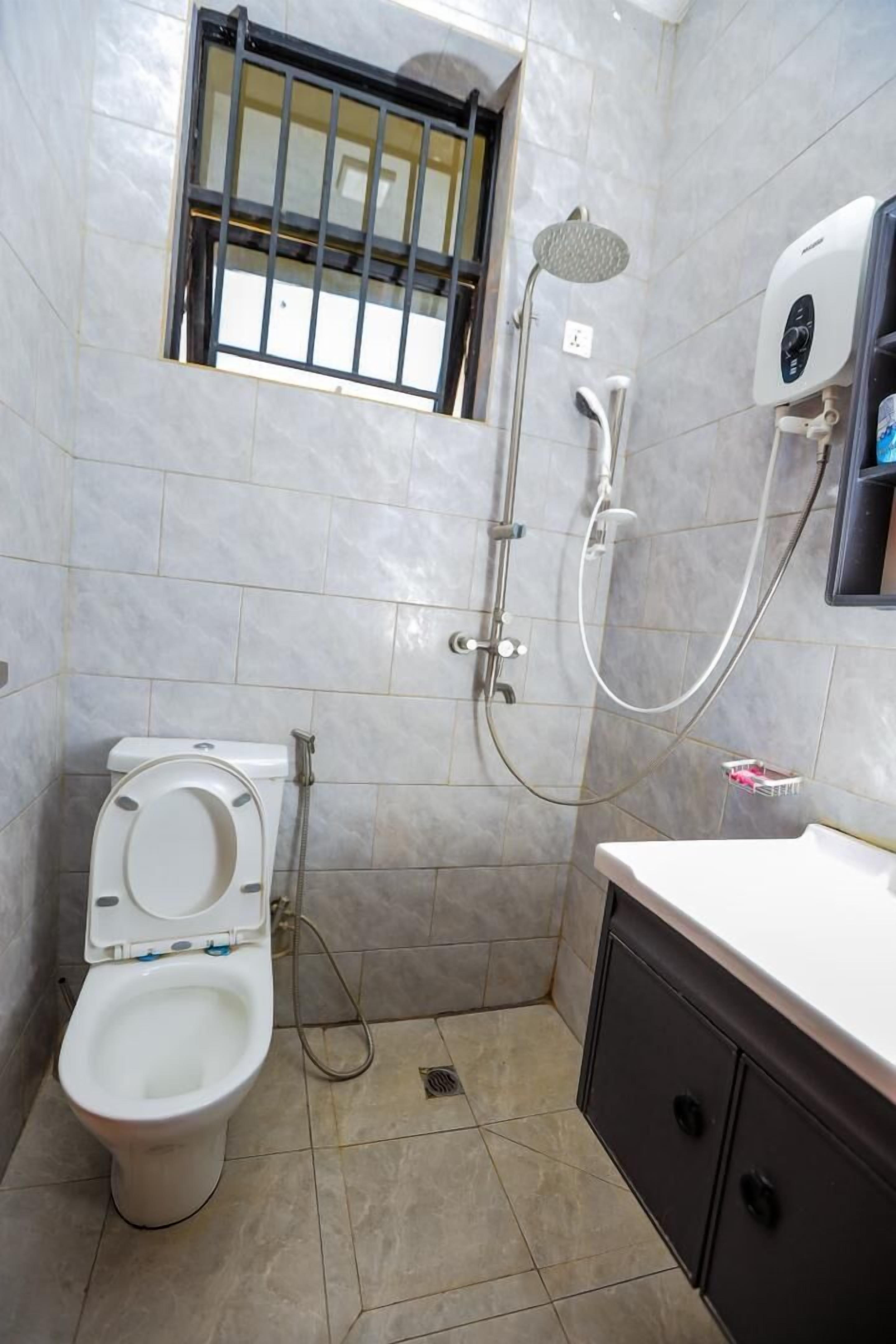 Een kleine badkamer met toilet, douche en wastafel.
