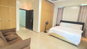 A hotel room with a bed, a sofa, and wooden wardrobes. - LUNARIS HOMES (Kigali)