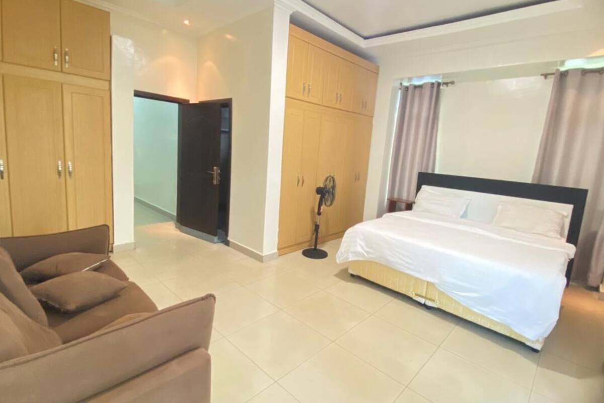 A hotel room with a bed, a sofa, and wooden wardrobes.