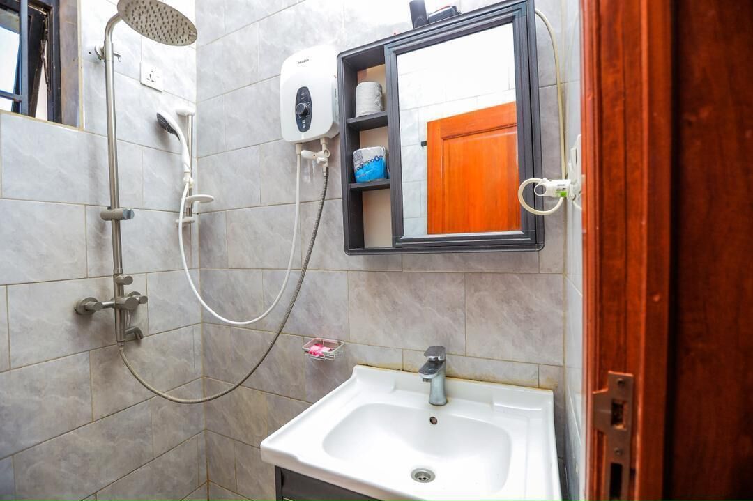 A bathroom with a shower, a sink, a toilet paper holder, and a mirror.