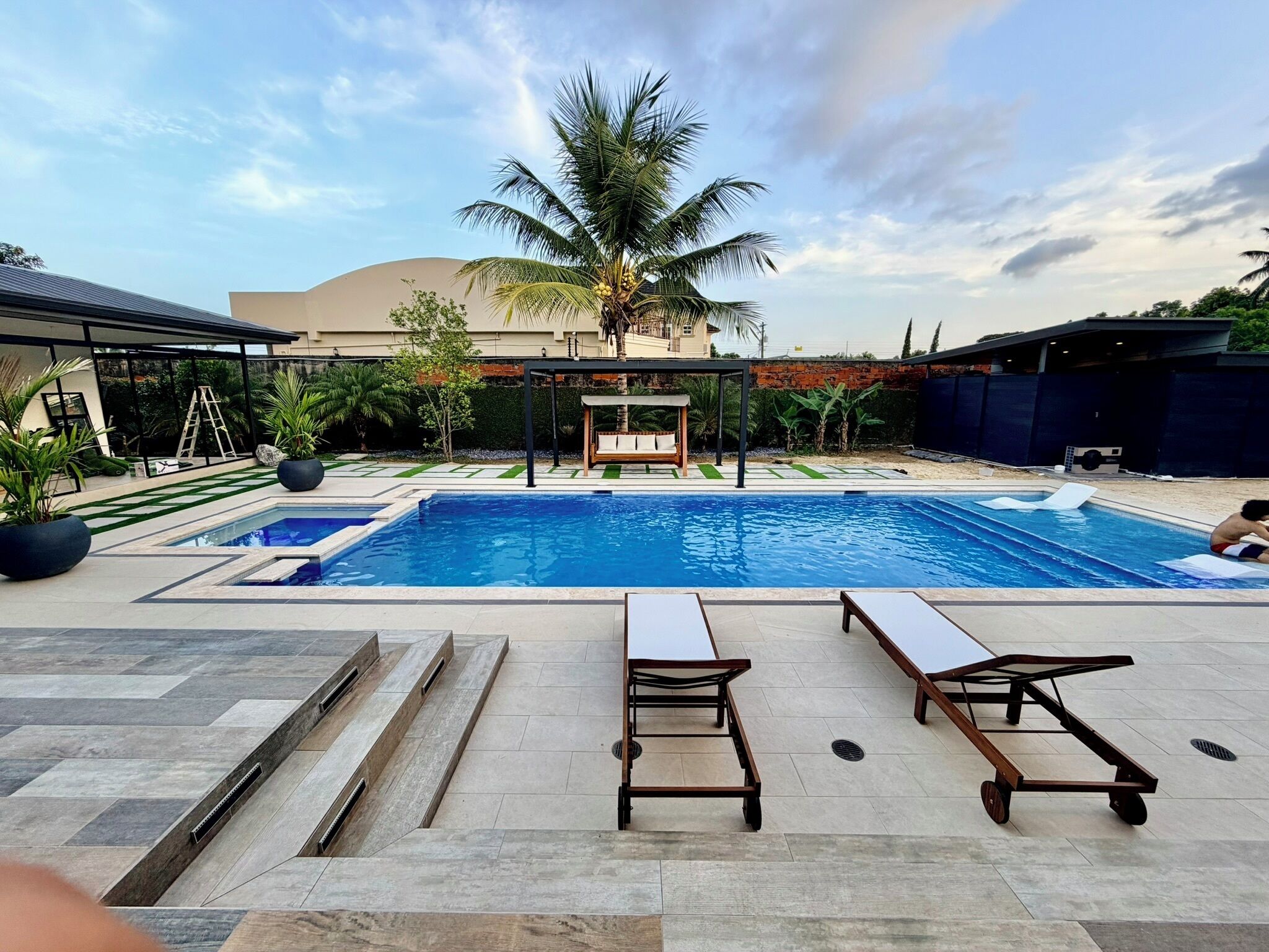 A swimming pool with lounge chairs and a palm tree.
