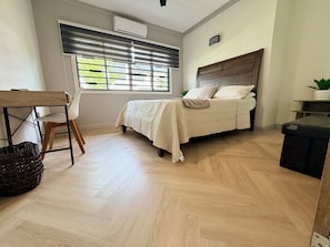 Une chambre à coucher avec un lit, un bureau, une chaise et une fenêtre avec des stores.