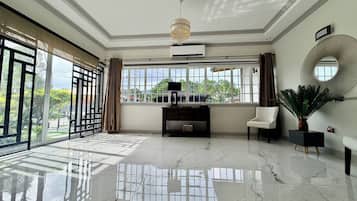 Une pièce spacieuse dotée d’un sol en marbre, de grandes fenêtres, d’un ventilateur de plafond et d’une console au design moderne.