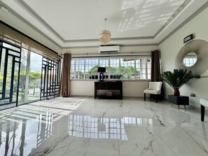 A spacious room with a marble floor, large windows, a ceiling fan, and a modern console table.