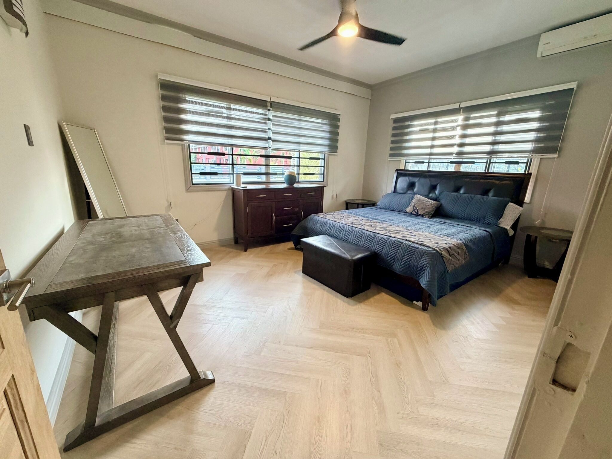 A bedroom with a bed, a desk, and a window with blinds.