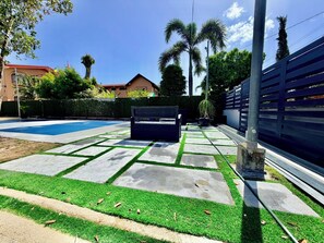 A backyard with a swimming pool, a bench, and a fence.