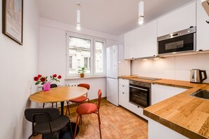 Eine moderne Küche mit weißen Schränken, einer Holzarbeitsplatte, einem eingebauten Ofen und einem Fenster mit Blick auf Gebäude.