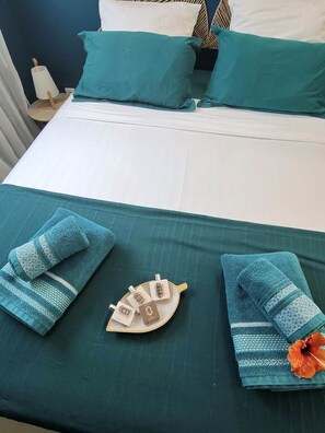 A neatly made bed with teal bedding, a set of towels, and a decorative item on the bed. - Koly'Dream - Ti Kozy - Villa with Pool in Saint-François (Saint-François)