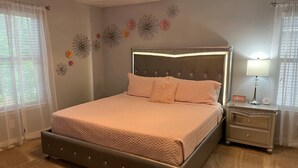 Une chambre à coucher comprenant un lit, une table de chevet, des éléments décoratifs sur les murs et un lustre.