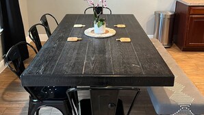 Une table à manger ornée d’une carte du monde, des chaises noires et un banc.