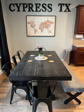 Une table à manger ornée d’une carte du monde, des chaises noires et un banc.