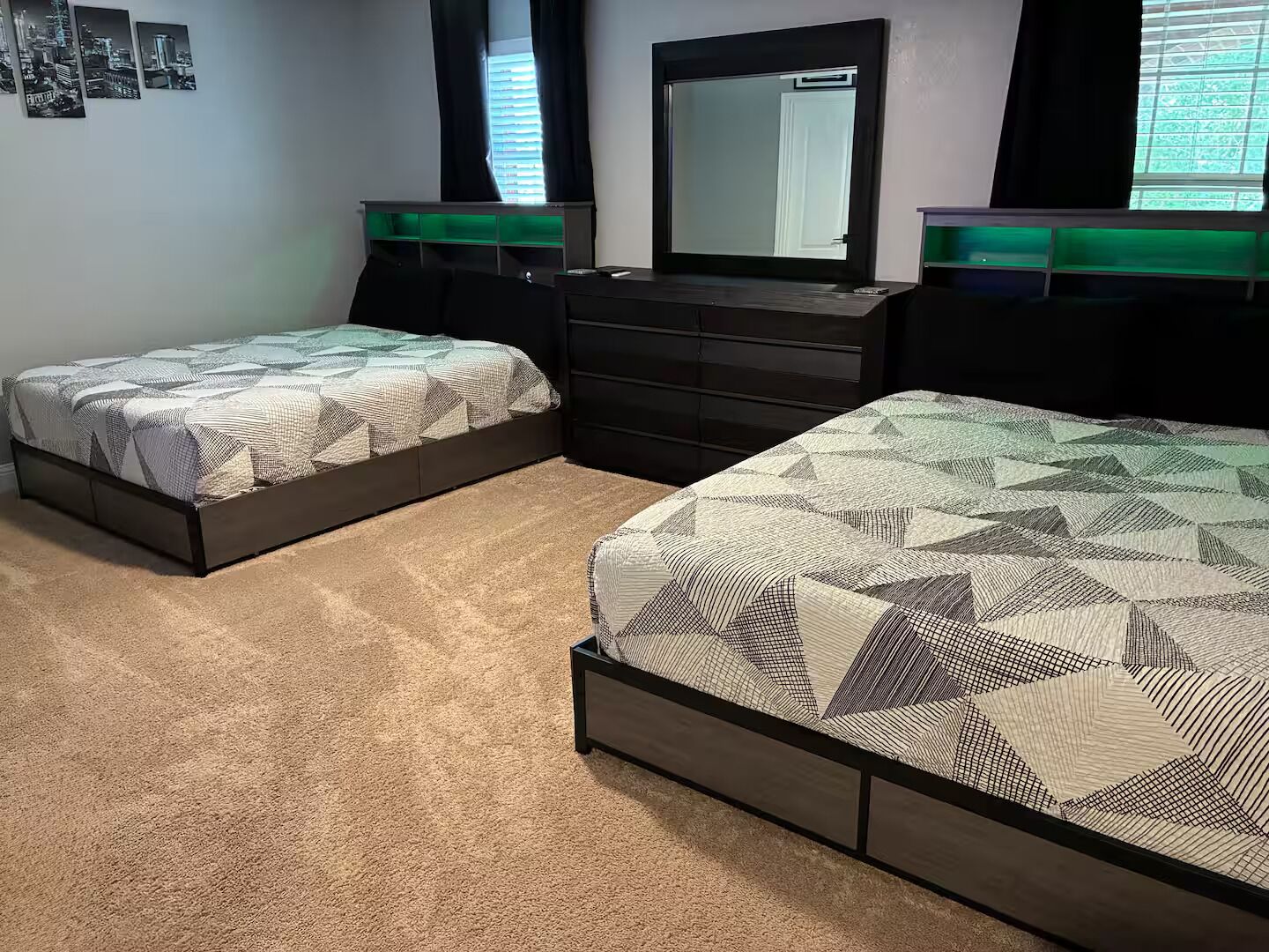 A bedroom with two beds, a dresser, and a mirror.