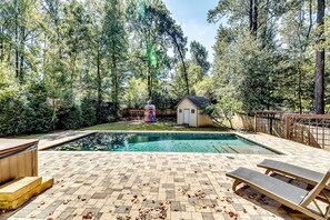 Ein Garten mit Schwimmbad, Whirlpool und einer kleinen Gartenhütte.