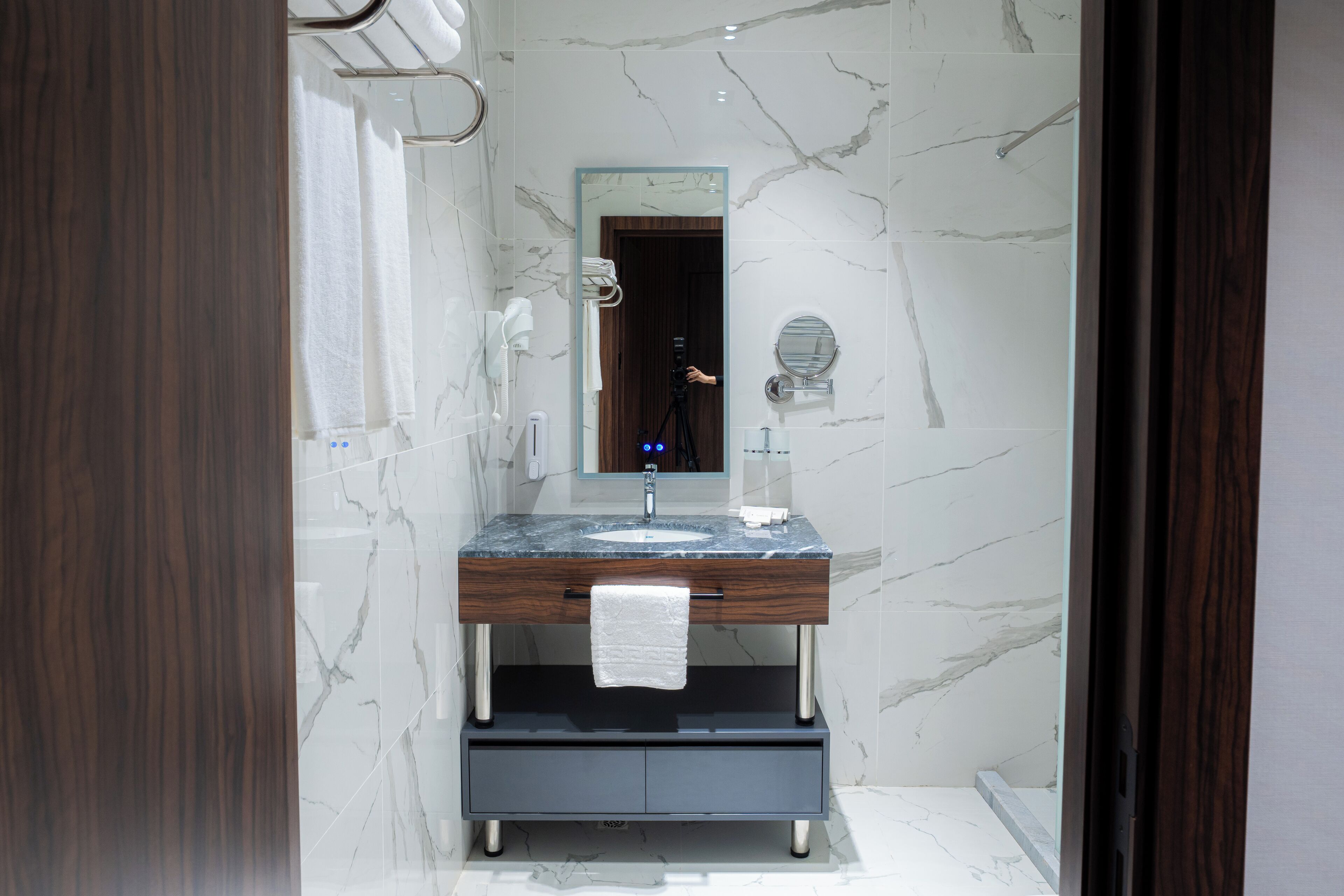 Un baño moderno con tocador de mármol, un espejo grande y una toalla colgando del lavabo.