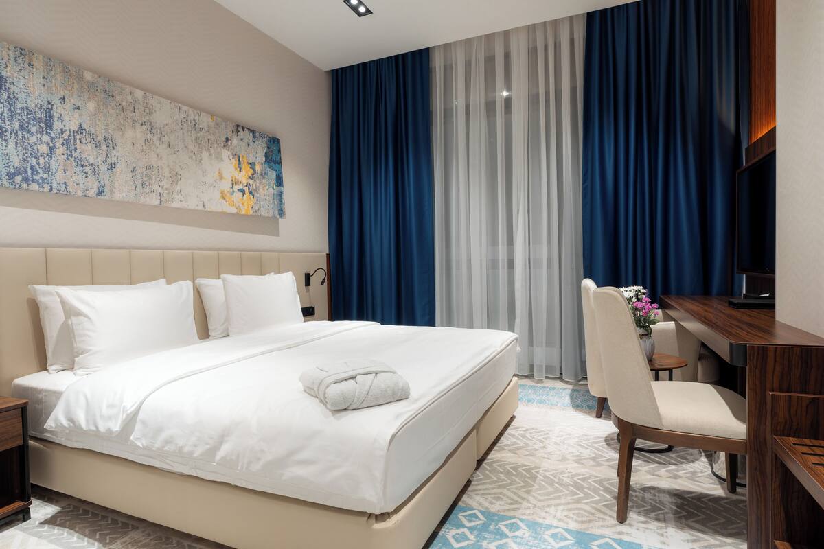 Una habitación de hotel con una cama grande, un escritorio, una silla y un televisor.