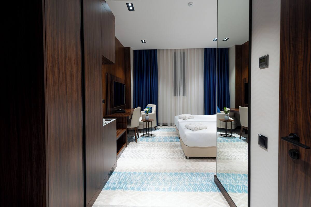 Una habitación de hotel moderna con una cama grande, un escritorio, una silla, un televisor y una pequeña mesa con una planta.