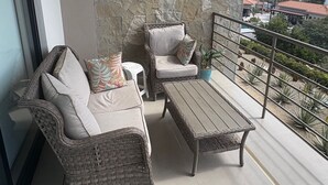 Een balkon met rieten meubels, een stenen muur en uitzicht op de stad.