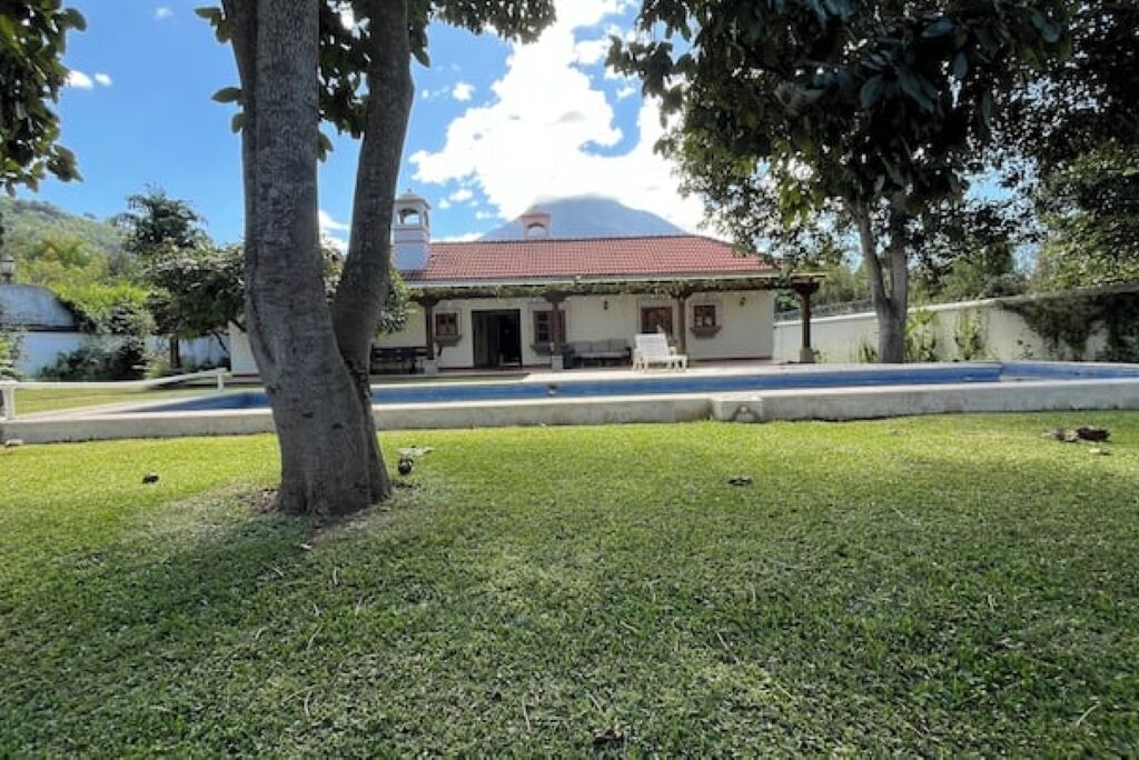 A house with a red roof, a small porch, and a lawn.