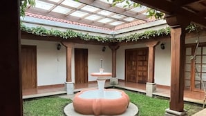 A courtyard with a central fountain, surrounded by stone steps and wooden doors. - Spacious oasis with pool and garden, minutes from Antigua. (Antigua Guatemala)