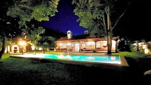 A house with a swimming pool at night, surrounded by trees and illuminated by exterior lights. - Spacious oasis with pool and garden, minutes from Antigua. (Antigua Guatemala)