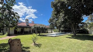 A well-maintained backyard with a swimming pool, a large tree, and a building with a red roof. - Spacious oasis with pool and garden, minutes from Antigua. (Antigua Guatemala)