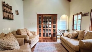 A living room with two beige sofas, a patterned rug, and a wooden door leading to another room. - Spacious oasis with pool and garden, minutes from Antigua. (Antigua Guatemala)