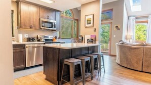 A modern kitchen with dark wood cabinets, stainless steel appliances, and a central island with stools. - Galena Getaway (Galena)