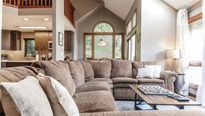 A modern living room with a sectional sofa, a coffee table, and a dining area with a kitchen in the background. - Galena Getaway (Galena)